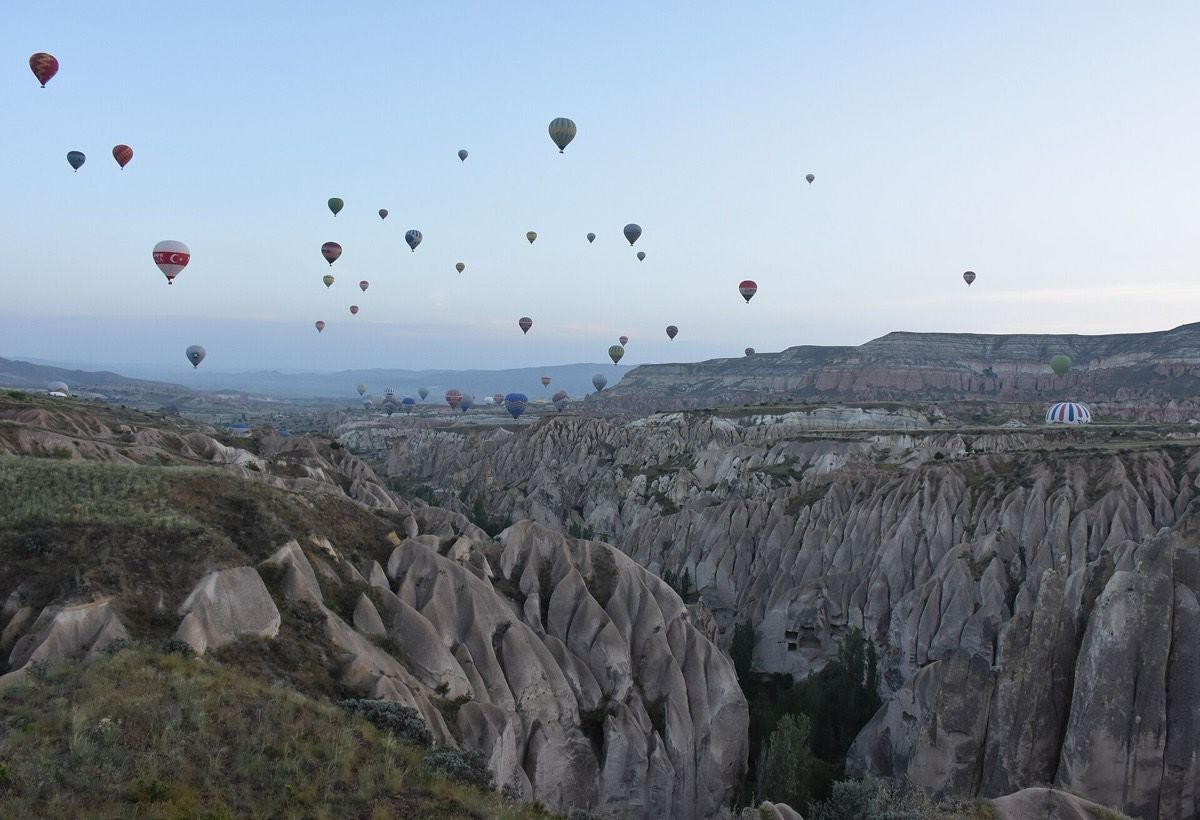Kapadokya'da şafakta vadilerin üzerinde sıcak hava balonları